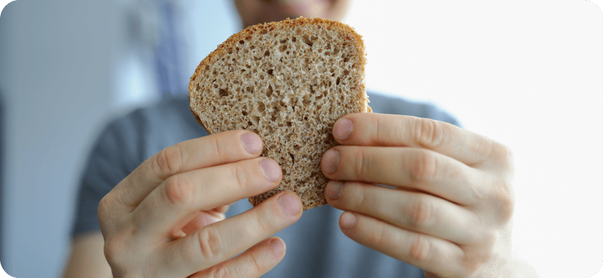 Hände, die ein Brot in einem Leinentuch halten